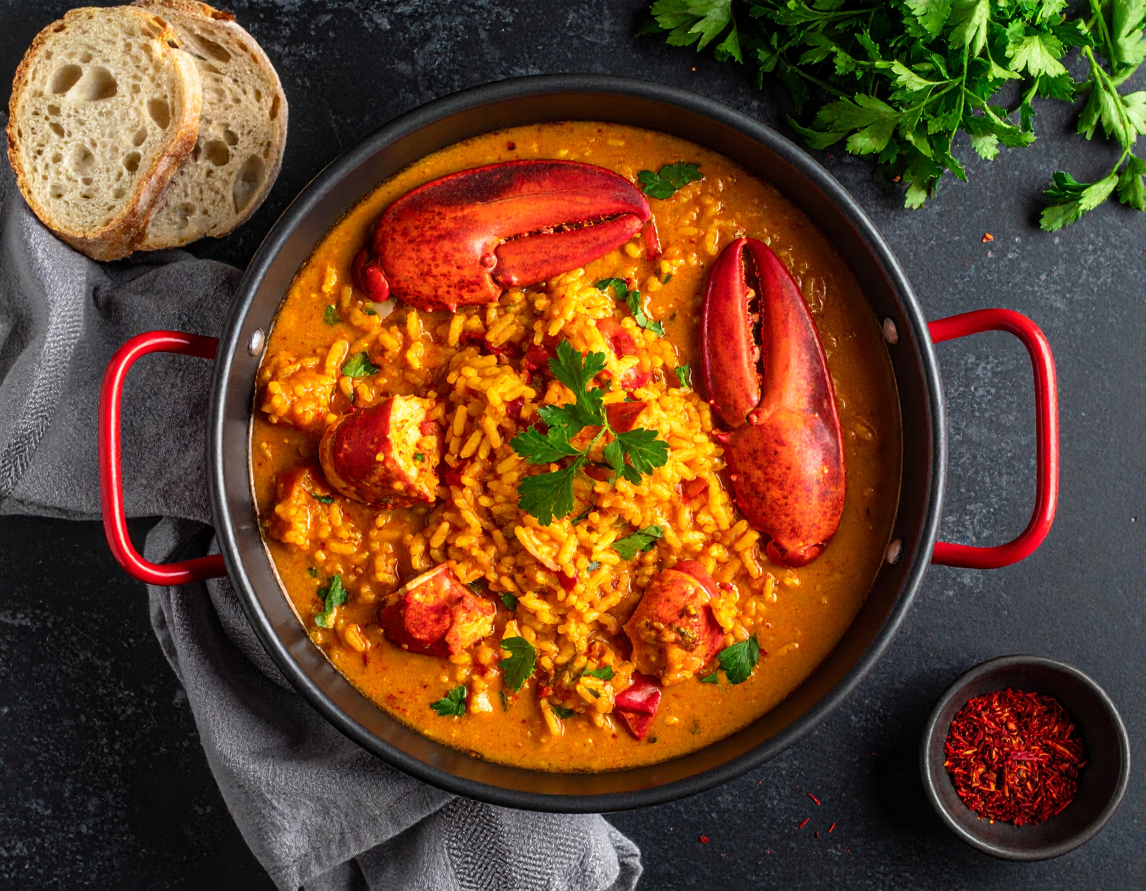 Arroz con bogavante en paellera roja con perejil y azafran