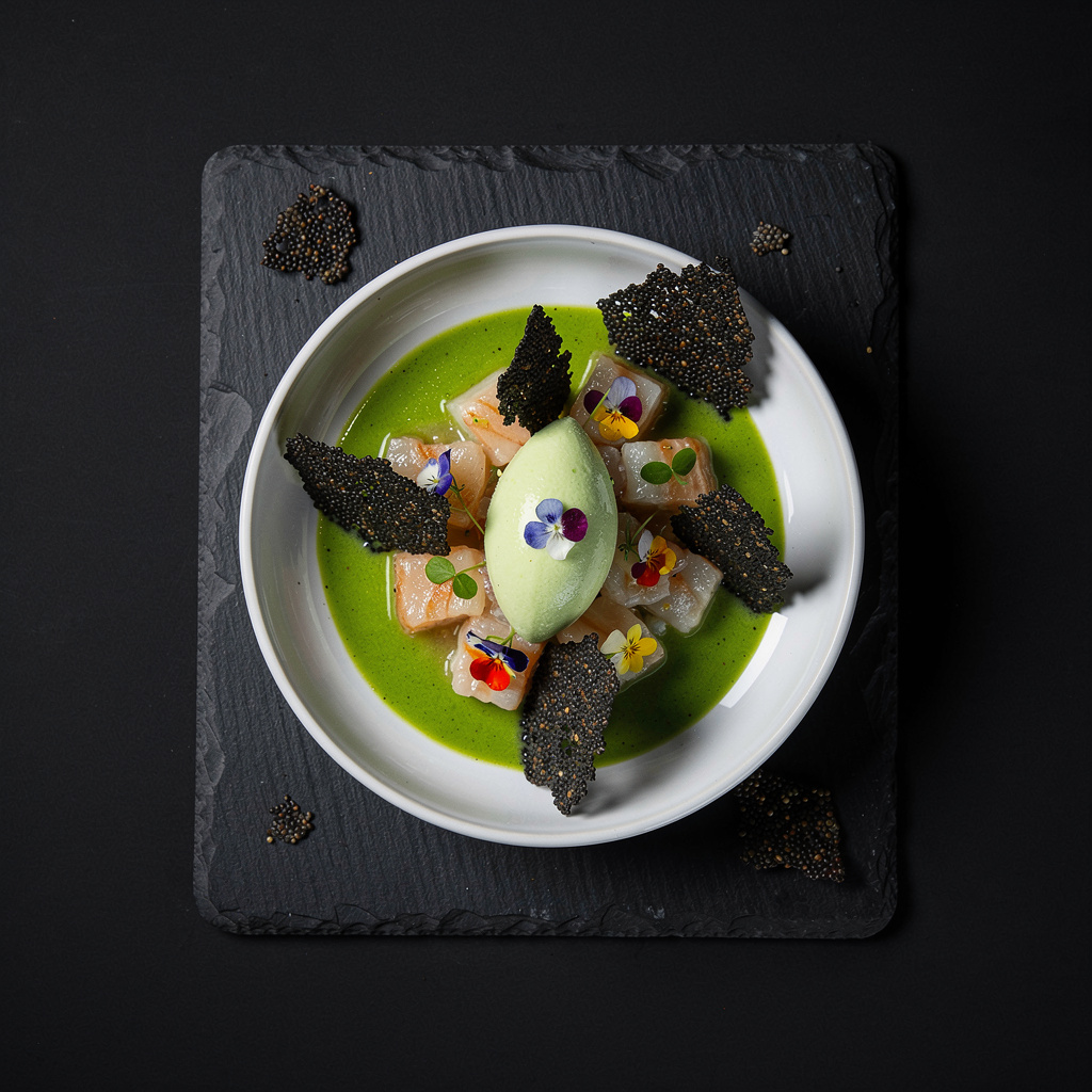 Ceviche de corvina salvaje en leche de tigre de maracuyá con aguachile verde de jalapeño, crocante de quinoa negra y helado de apio en cuenco de cerámica blanca