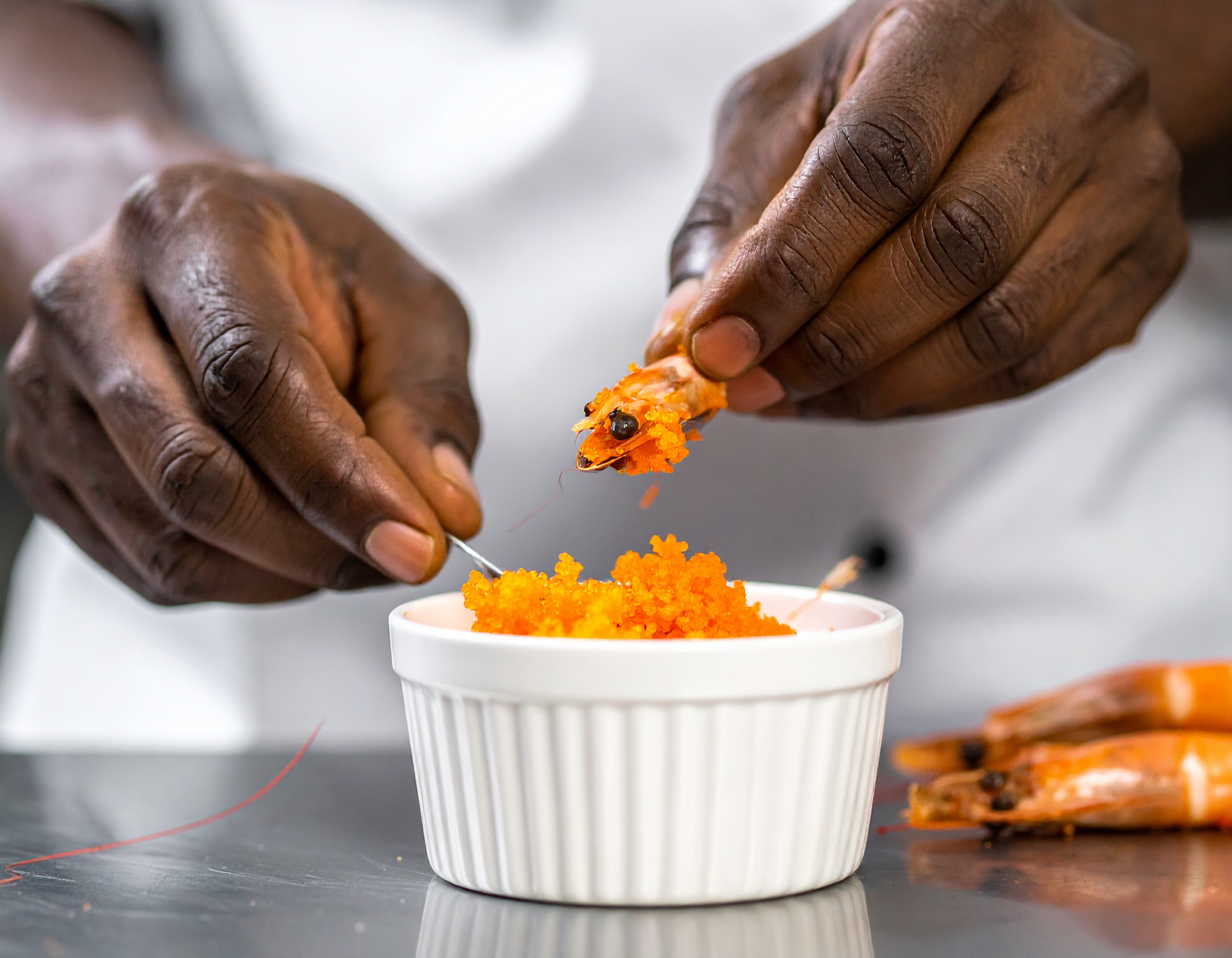 Coral naranja vibrante extraído de las cabezas de gamba roja en ramekin blanco