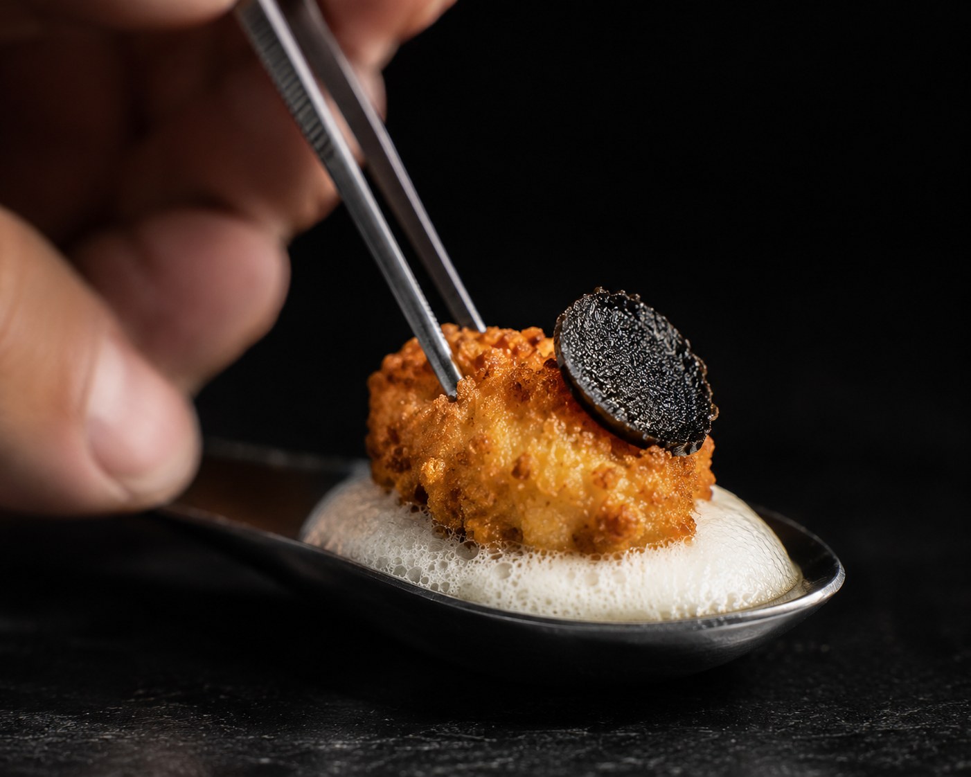 Montaje en cucharilla: espuma, kokotxa frita y ajo negro