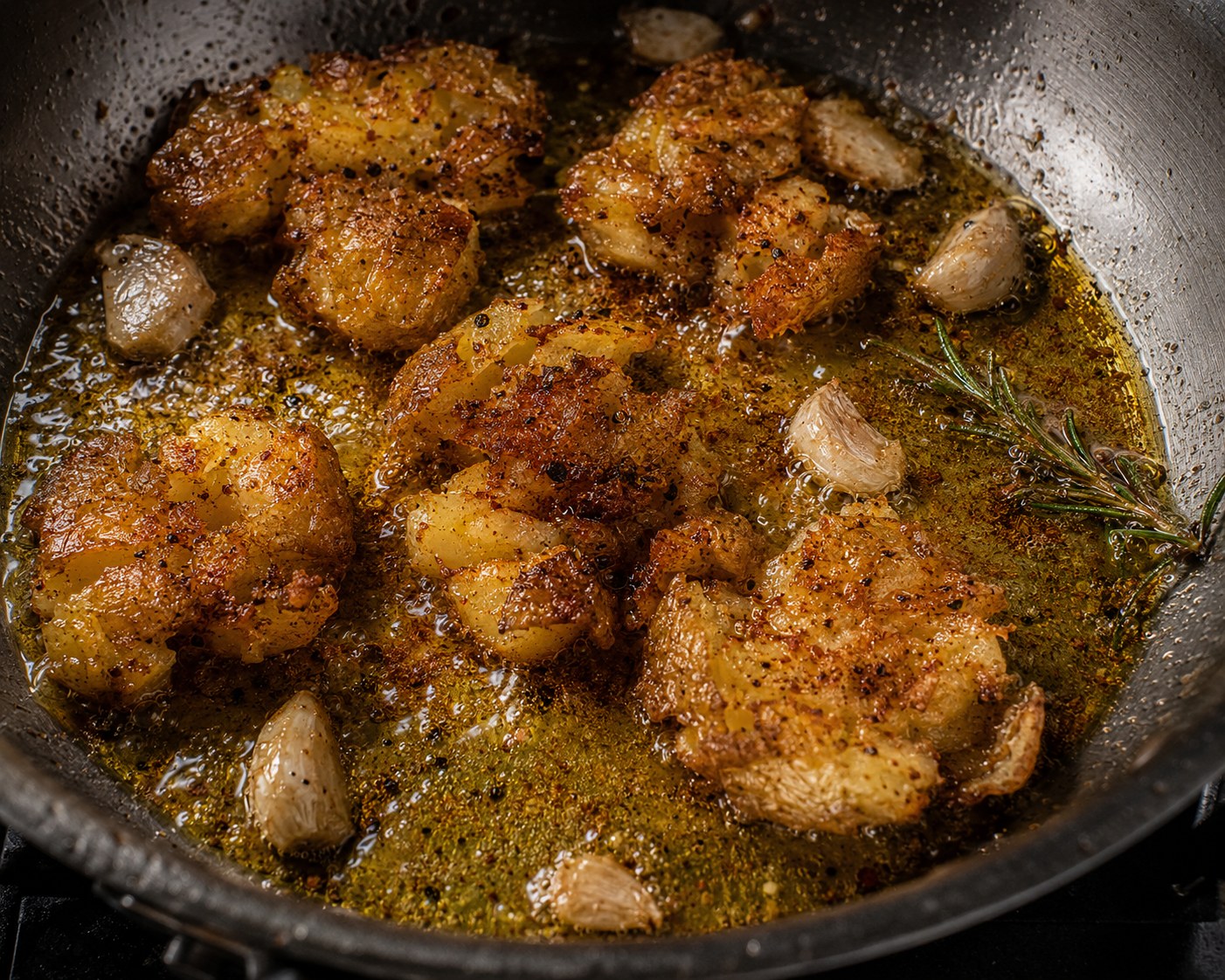 Patatas rotas friéndose doradas con ajo y romero