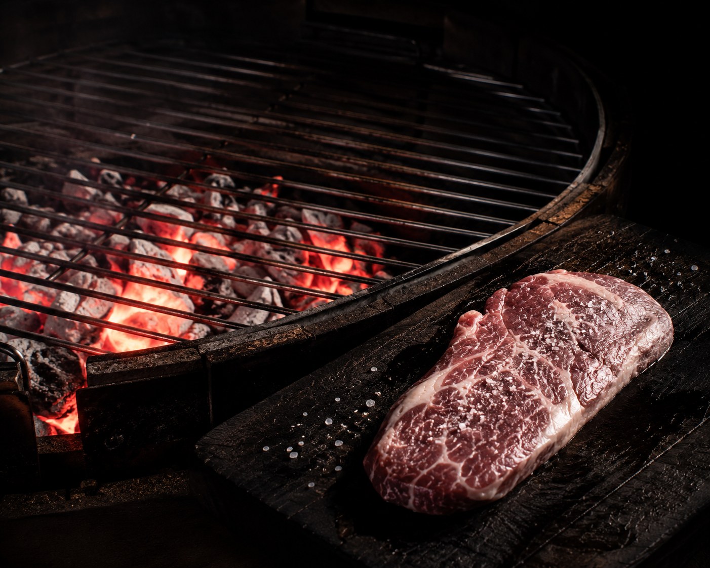 Brasas de encina grises-blancas listas, presa salada junto a la parrilla