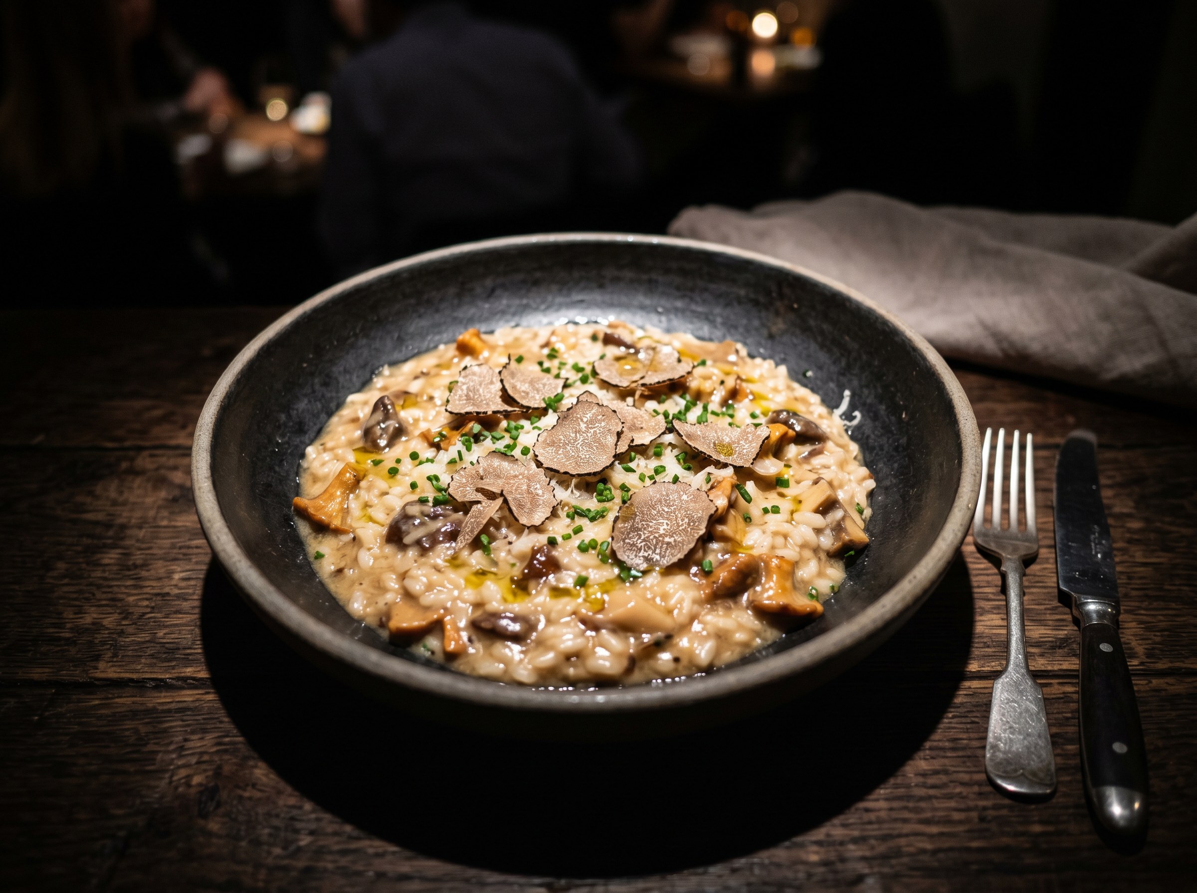 Risotto de hongos con trufa negra y aceite de trufa en cuenco artesanal de ambiente