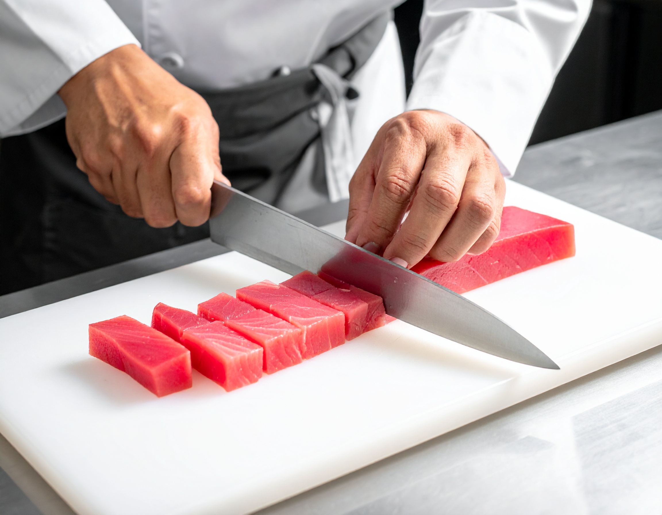 Chef cortando el lomo de atún en cubos perfectos con cuchillo japonés