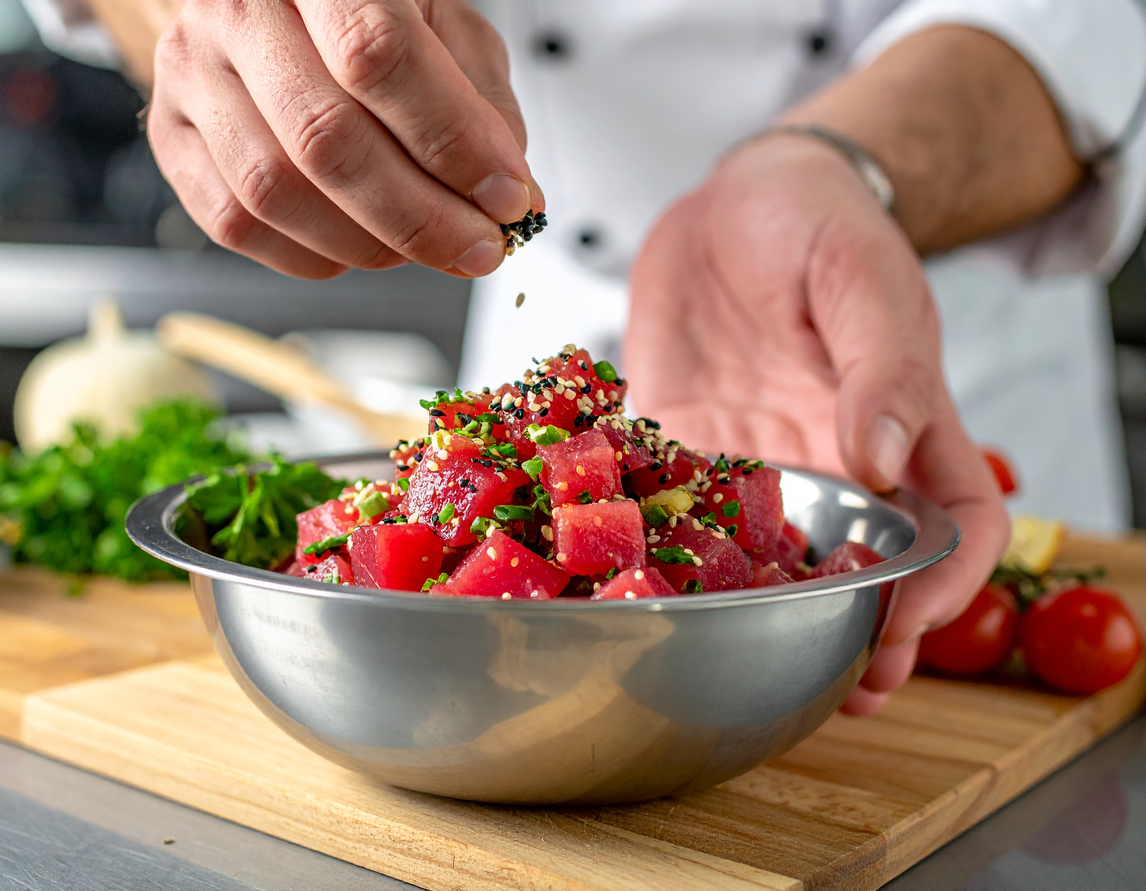Chef aderezando el tartar de atún con sésamo y ponzu en bol de acero