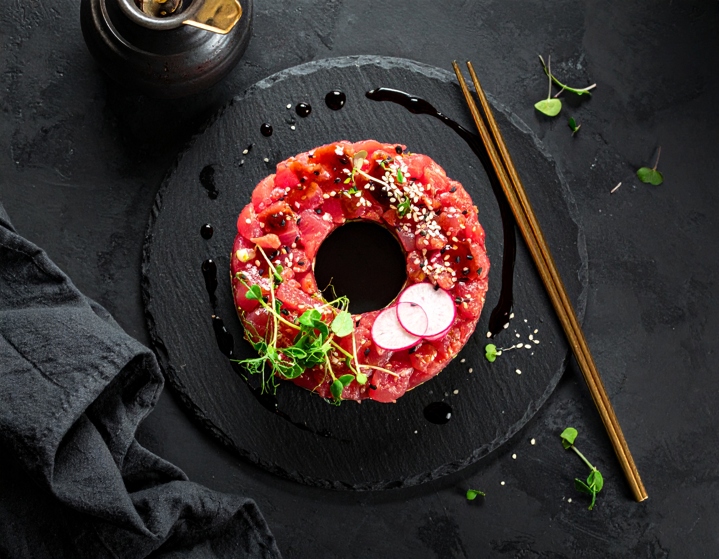 Tuna tartare elegantly plated with microgreens, dark slate background, atmospheric lighting