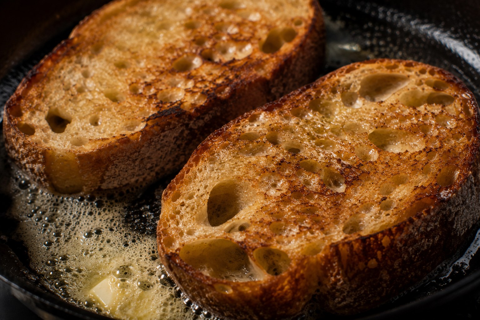 Rebanadas de masa madre tostándose en mantequilla hasta dorado profundo